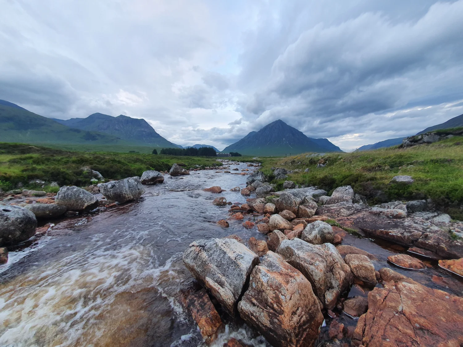 The River Etive tumbling over boulders near Black Corries, with Buachaille Etive Mòr standing at the head of the glen under a clouded sky