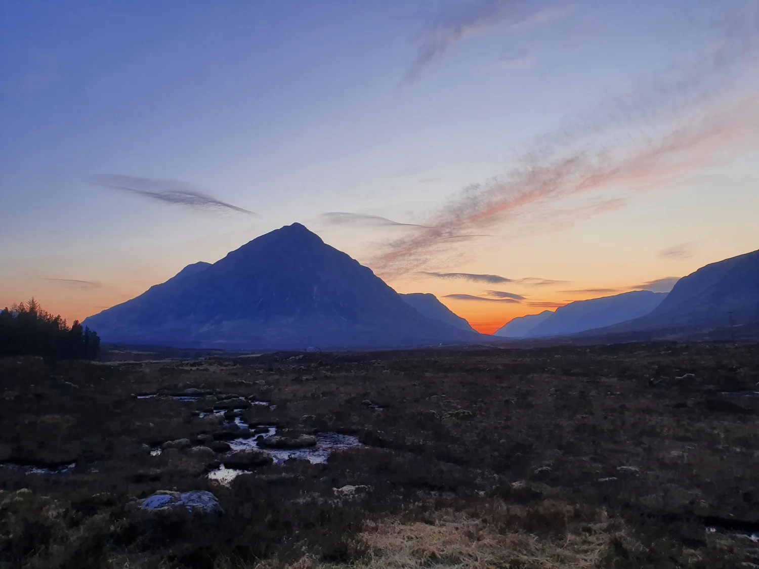 Buachaille Etive Mòr silhouetted against a pink and orange sunset sky above the open moor