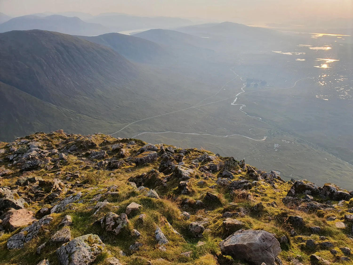 Looking down over Rannoch Moor from the summit of Stob Dearg towards Kingshouse, where Tigh na Coille sits, with the loch catching the evening light beyond